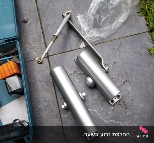 שני צילינדרים מתכתיים וכלי עבודה על רצפה אפורה